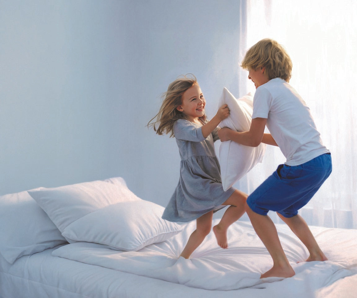 Kinder spielen unbeschwert auf einem Bett mit milbendichten Bezügen